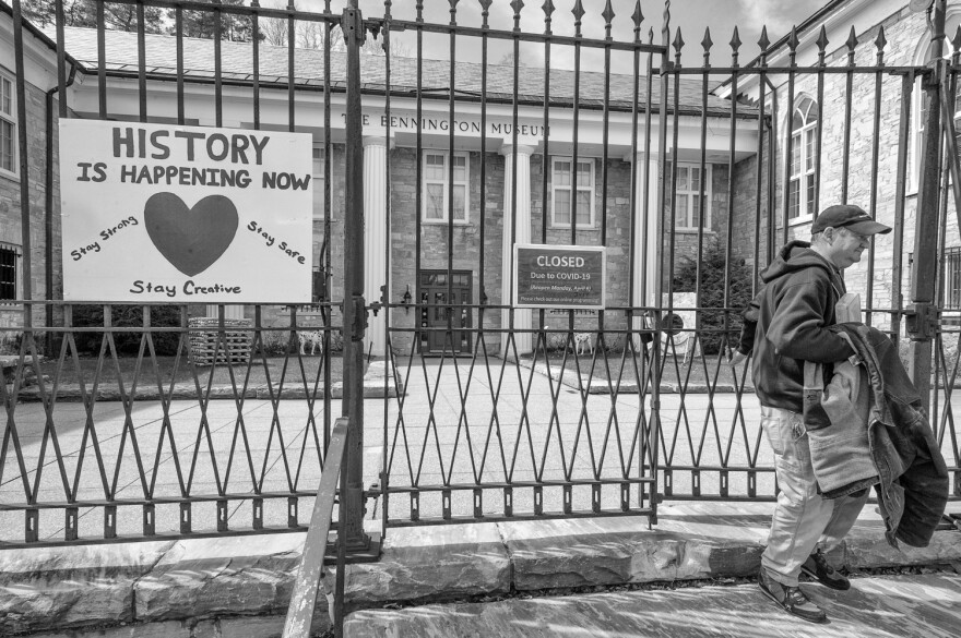 A black and white image of a poster on a fence with a man exiting. 