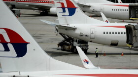 Malaysia Airlines ground staff walk past Malaysia Airlines aircraft parked on the tarmac at the Kuala Lumpur International Airport in Sepang in 2016. (Manan Vatsyayana/AFP/Getty Images)