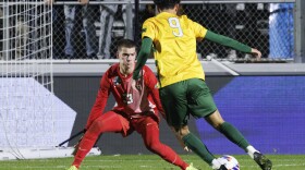 A soccer goalkeeper defends against another player moving ahead with the ball