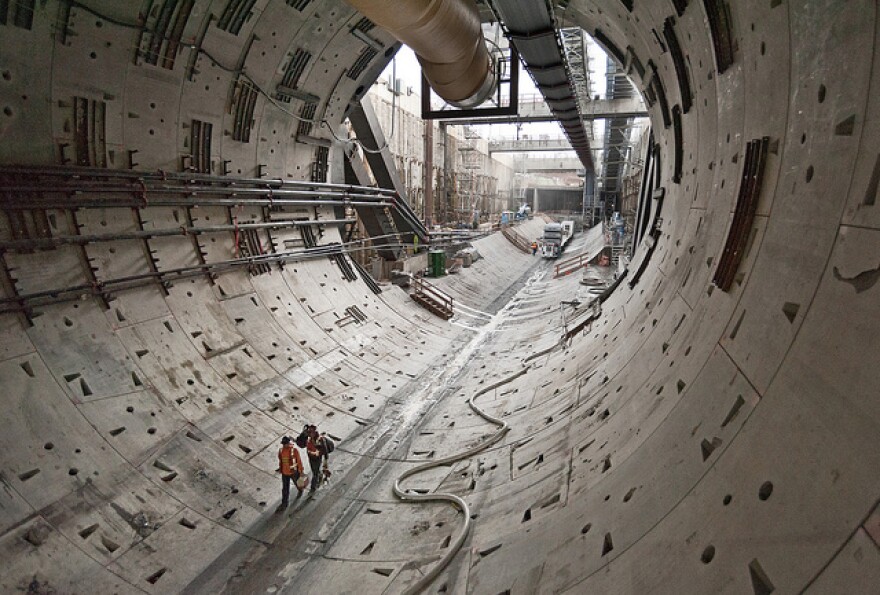 Two workers walk through the first rings of the tunnel toward Bertha, the SR 99 tunneling machine.