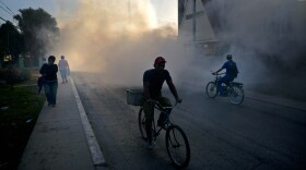 People in Pinar del Rio, Cuba, make their way through a fumigation fog that's meant to kill the mosquito that transmits the Zika virus.