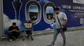 A foreigner walks past a sign board for the Baiyun airport in Guangzhou in southern China's Guangdong province on Nov. 6, 2025.
