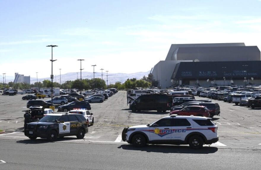Police cars in a parking lot of a building on the right. Mountains are visible in the background.