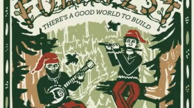 Image of two people sitting in tree branches wearing green long sleeves, red pants, and a red cap on. One person has a beard. The person with a beard is playing the banjo, the other is playing the flute. The poster is for Folk Fest which is written in tree branches. It reads "Folk Fest There's a good world to build". 