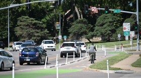 A man riding a bicycle uses a bike lane next to traffic along a busy street. The intersection shows it is located at 39th Street and Gillham Road.
