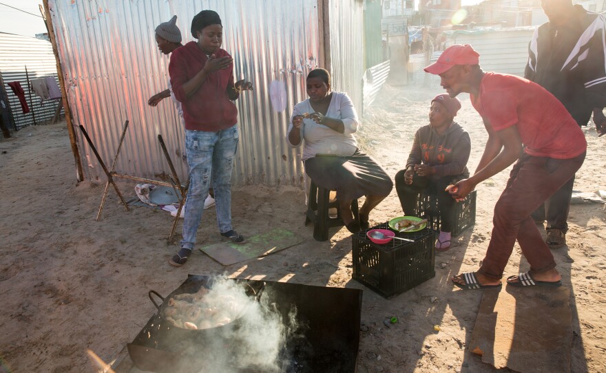 Many residents don't having proper cooking facilities in their shacks (or money to buy items in bulk). So street food is common. Linda Maseko (left, wearing jeans) has a bite with other residents.