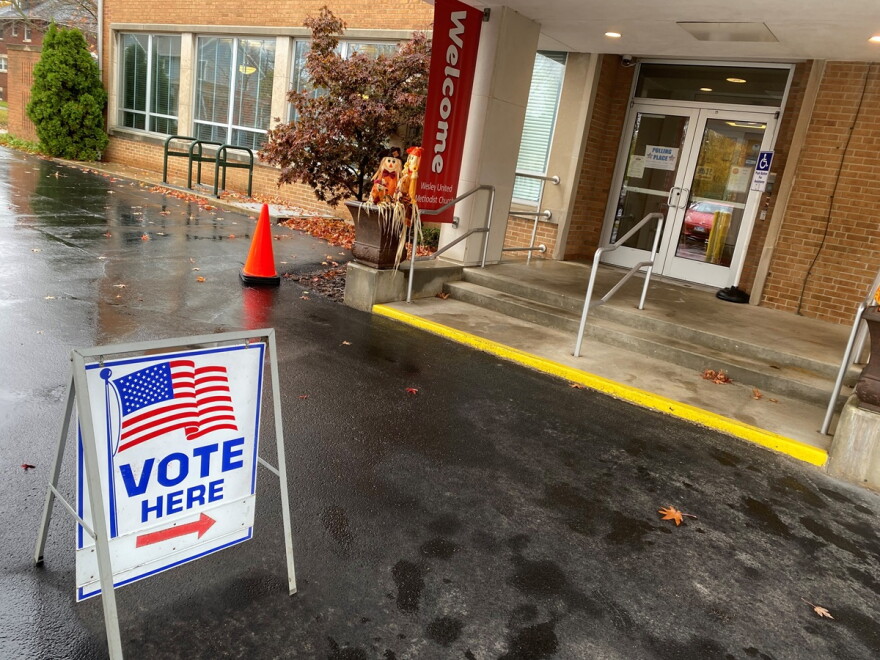 Building entrance with a 'Vote Here' sign on the pavement outside