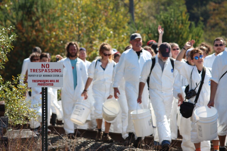 Protesters march down railroad tracks past a "no trespassing" sign near Merrimack Station Saturday.