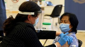 A health care worker administers a Pfizer-BioNTech COVID-19 vaccine to personal support worker Anita Quidangen at The Michener Institute, in Toronto, Canada, on Monday. Quidangen was one of the first people in Canada to receive the shot.