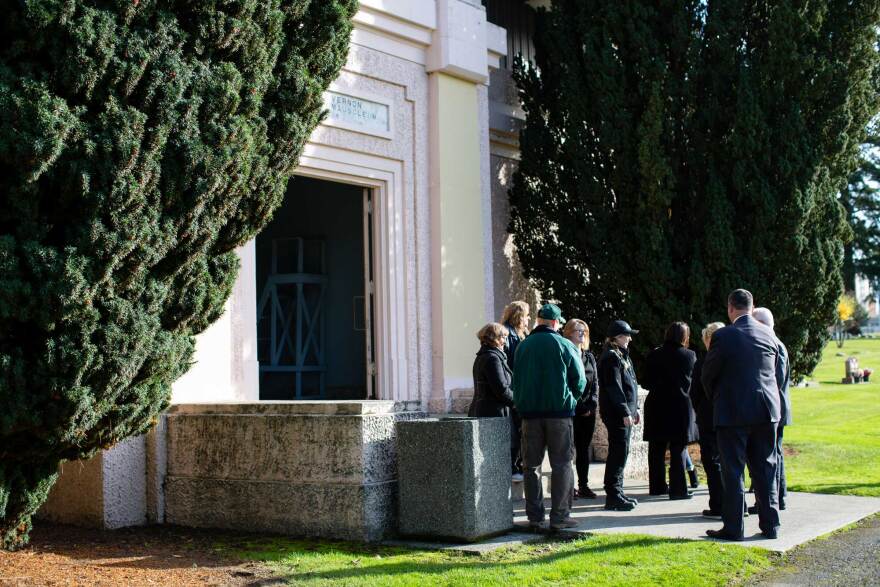 A small crowd of county officials gathers outside the mausoleum at Mount Vernon Cemetery, during a committal service for 25 people whose remains went unclaimed over the past two decades.