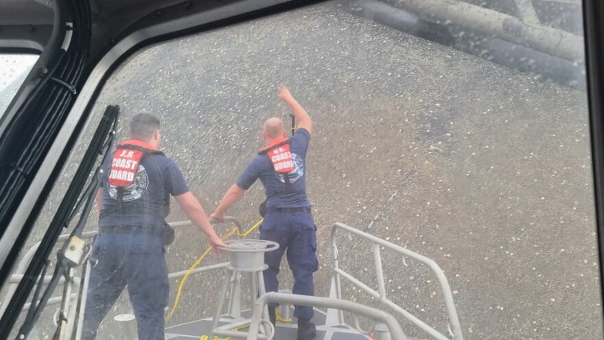 Coast Guard crew members attempt to throw a hammer at the hull of the SeaCor Power, in an attempt to make contact with potential survivors inside the vessel.