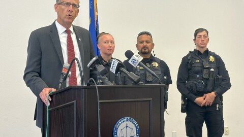 Washoe County District Attorney Chris Hicks is at the podium talking about the vandalism incident. To his left are Washoe County School District Police Chief Seana Baker, school police officers Eric Diamond and Megan Lytle.