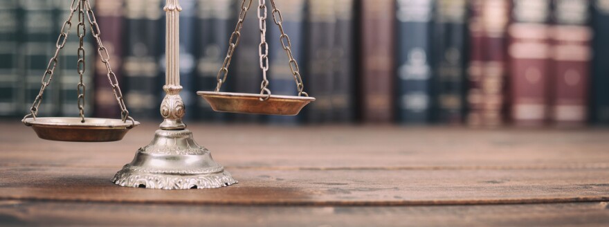 Scales of Justice and Law books on a wooden background.