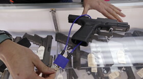 A gun shop owner demonstrates how a gun lock works on a handgun.
