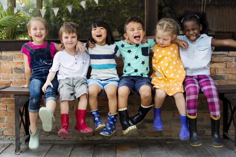 Group of kindergarten kids friends arm around sitting and smiling fun