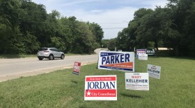 Election signs advertising many different candidates for city offices crowd a grassy hillside along a road in Fort Worth.