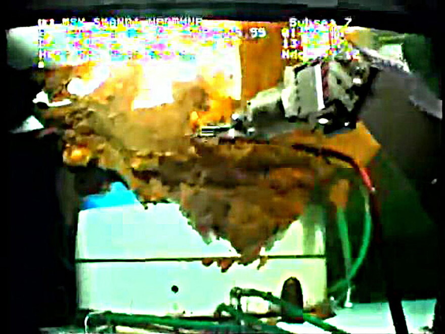 A robotic arm from a submersible works around the leaking Gulf of Mexico wellhead in this still image from a live BP video feed.