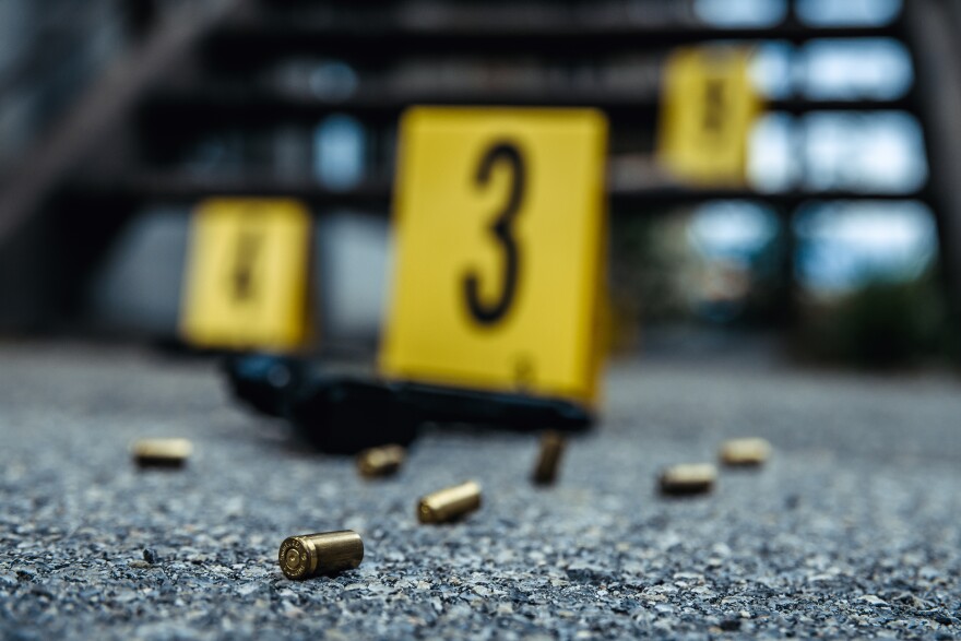 Bullet casings and gun on asphalt. Crime scene.