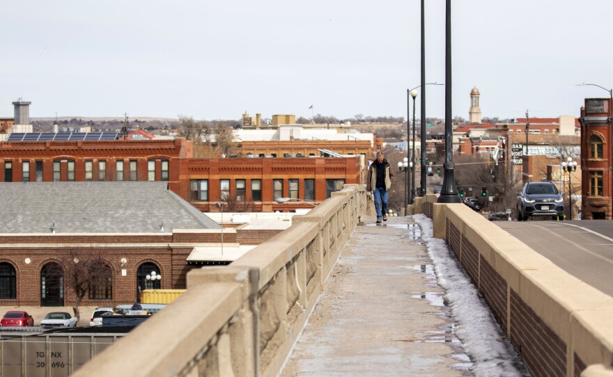 A person walks across a bridge over the Arkansas River in Pueblo. The city is aiming to redefine its economy, and its politics following decades as a solidly blue collar Democratic stronghold.