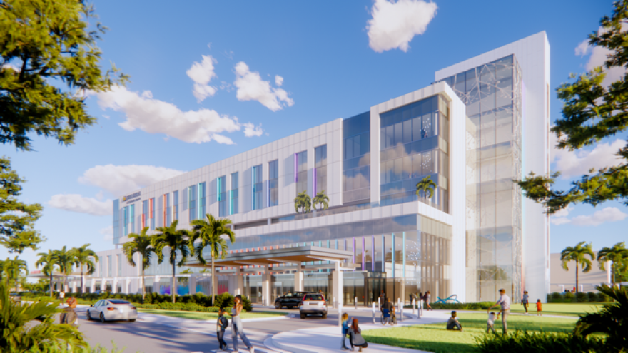 A computer rendering showing a modern hospital facility set against a blue sky, with green trees in front of the entrance.