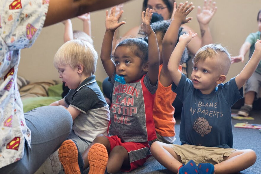 Children in a class for 2-year-olds at a Norman daycare center raise their hands during a song in July 2018.