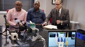 From left, interpreter Israel Siku, Peter Lyoya, and attorney Ven Johnson watch, Thursday, June 9, 2022, in Detroit as Kent County Prosecutor Chris Becker explains his decision to charge Grand Rapids police Officer Christopher Schurr with second-degree murder during a press conference at the Michigan State Police sixth district headquarters in Walker. Schurr fatally shot Black motorist Patrick Lyoya on April 4. (AP Photo/Carlos Osorio)