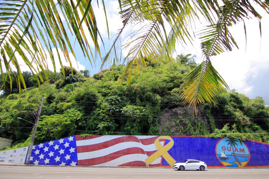 Afternoon traffic passes in front of a mural depicting the U.S. and Guam flags in the Tumon district on the island of Guam.