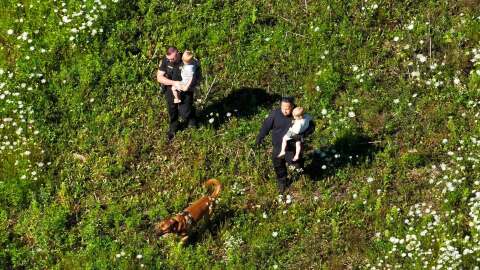 Menominee County Sheriff's deputies and K-9 Kado carry two children away from a field