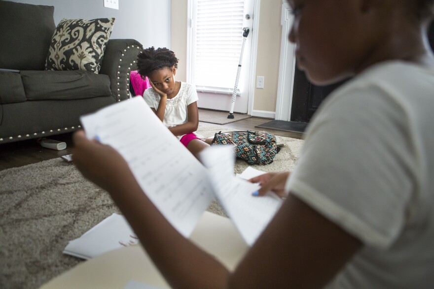 Karisma Clark, left, watches as her sister Kaiden Clark, right, organizes the lesson plans she put together to teach Karisma in their at-home "school". Kaiden is both the principal and the teacher while Karisma is the student who must do her homework and complete reading assignments. They have a school schedule that they follow each day. Usually each "class" is about an hour, but Kaiden admits, "the classes I really don't want to teach are like 20 minutes, like P.E."