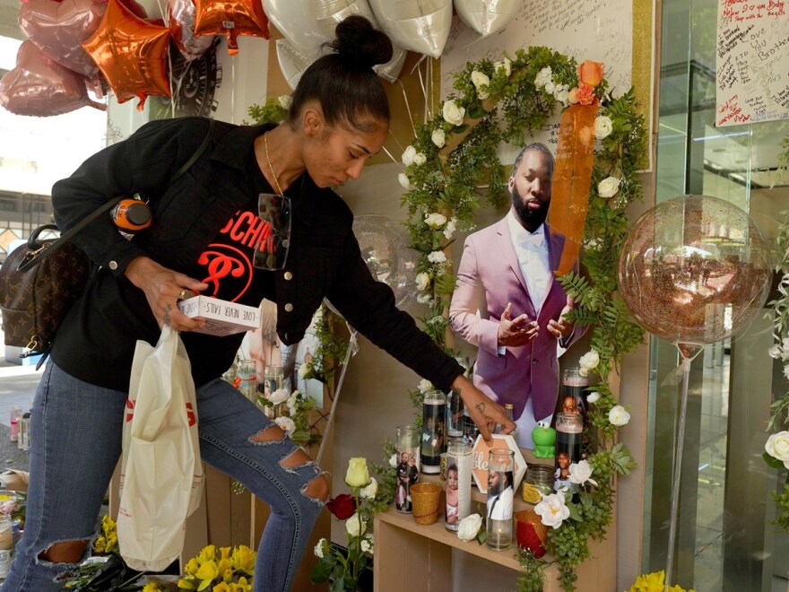 Kay Harris, the sister of shooting victim Sergio Harris, places a decoration by a photo of her slain brother at a memorial in Sacramento, Calif., Thursday, April 7, 2022.