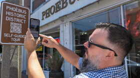 Neighborhood Commissioner Joe Griffith demonstrates how to try out the Phoebus self-guided walking tour using new signs around the neighborhood on Thursday, May 30, 2024.