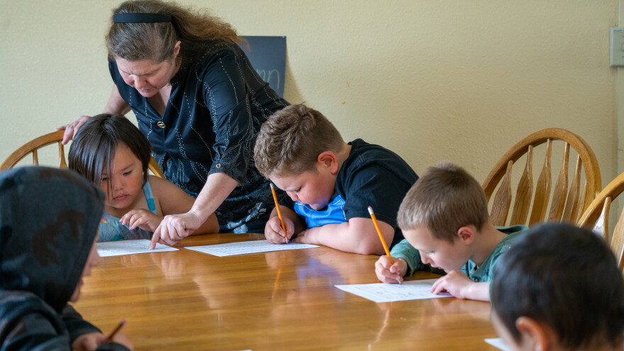 Teacher Lynette Hull assists students with a worksheet assignment at the Nikolski School's large, gathering table.