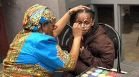 Before a screening of "Black Panther," artist Martha Walker-Dawkins paints the face of Zaniah Welsh, a fourth-grader at West Hartford's Smith STEM School. Engineer David Johnson sponsored the event to inspire students.