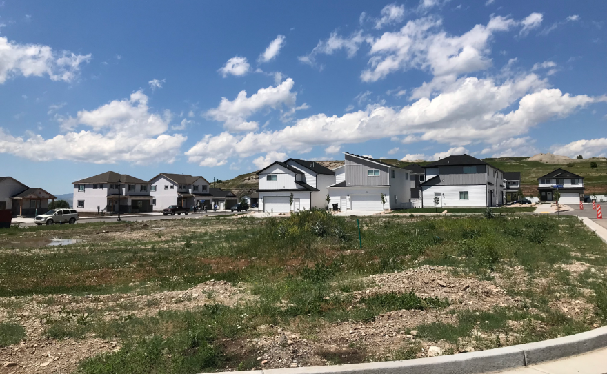 A row of houses leading into a cul-de-sac across a patchy field of grass.