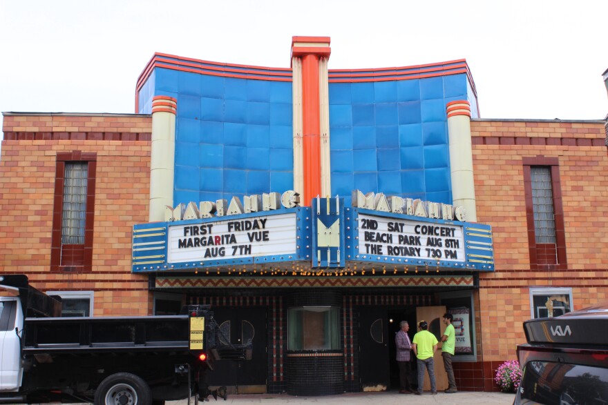 A shot of the outside of the Marianne Theater. A Bellevue Public Works truck sits outside, and two workers talk with the mayor. The city does some mild renovations to keep the building from completely deteriorating. 