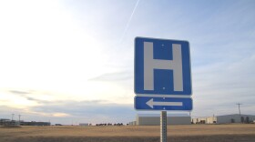 A photo shows a road sign pointing to the nearest hospital.