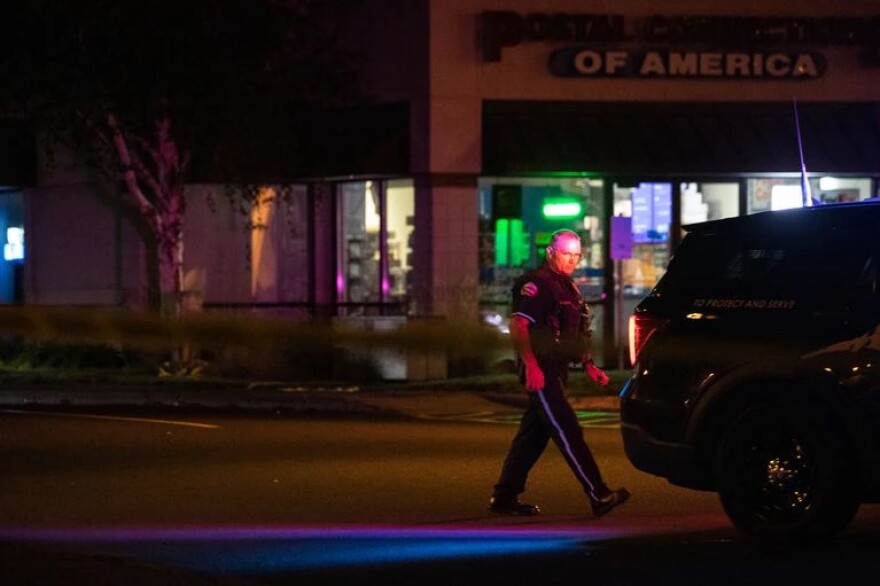 A Bend police officer monitors the crime scene after a shooter opened fire at a Safeway grocery in Bend, Ore., Sunday, Aug. 28, 2022, killing at least two people.