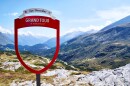 A view of San Bernardino Pass, a destination of the the European Grand Tour, Schweiz. Snow covered mountains and rolling valleys against a blue sky with wispy clouds.
