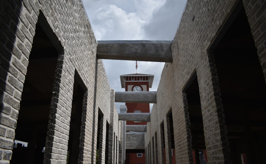 A clock tower is visible through stone columns of another building.
