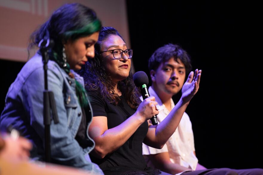 Two women and a man address an audience. 