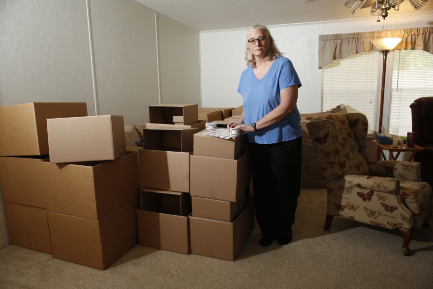 Melissa Preen stands beside boxes filled with her belongings as she prepares to move back to Cleveland, Ohio. She says she can no longer afford to live in Country Villa Estates in Riverview, Florida, due to rising lot rent and other fees.