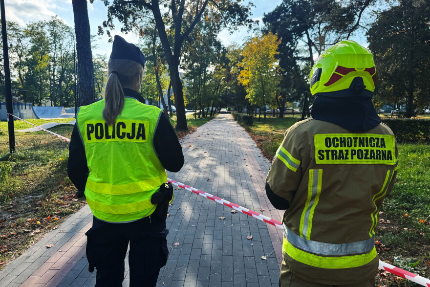 A police officer and a volunteer firefighter look down the street near a cordoned-off area following an attack on the Vocational School Complex No. 4 in Ostroleka, Poland, Wednesday, Oct. 7, 2026.