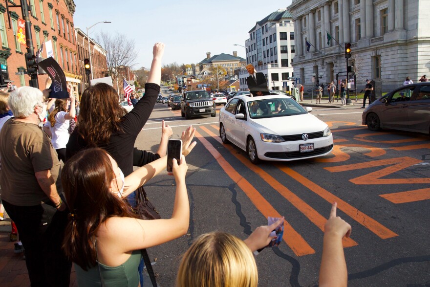 people point to a car with a biden cutout in the sunroof along Burlington's Main Street