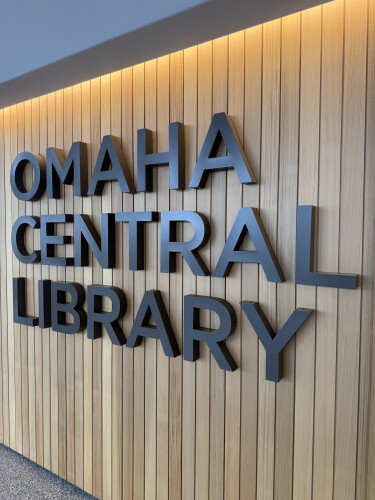 Dark letters reading Omaha Central Library mounted on a warm wood-slat wall
