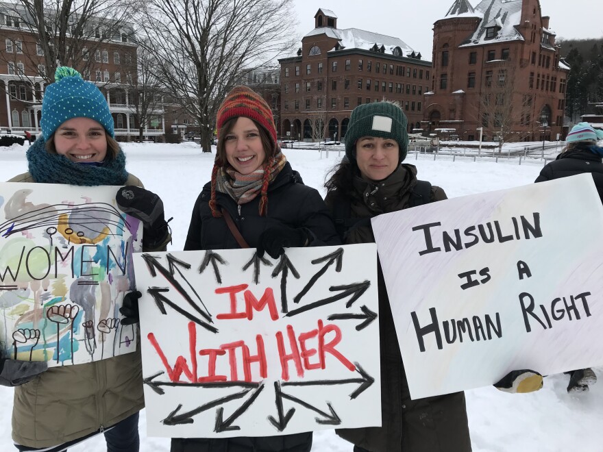 Three woman hold signs at the 2019 Women's March