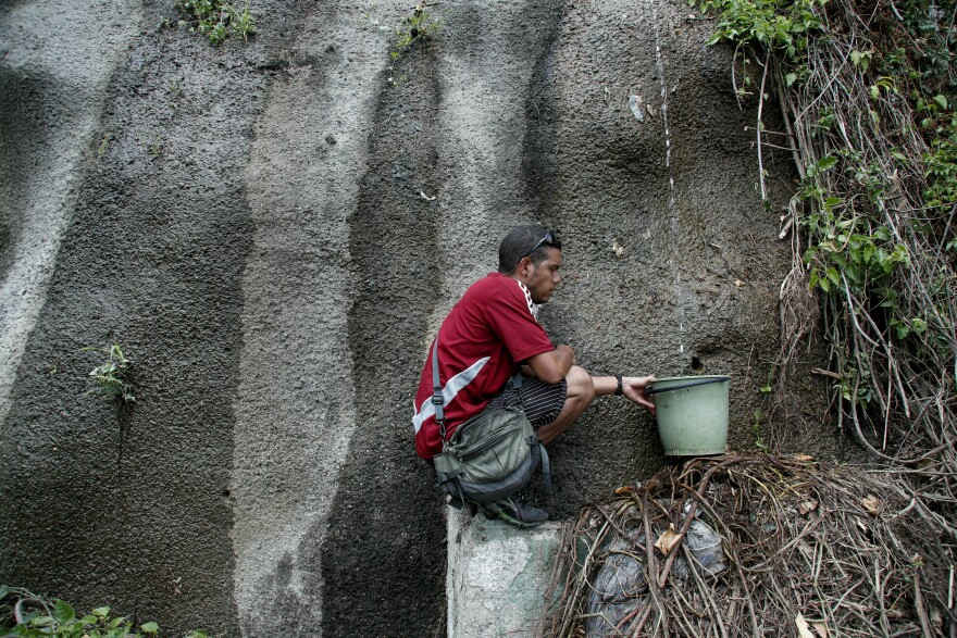 A man collects water in El Ávila National Park during Venezuela's blackout, which has affected the water pumps in people's homes and apartment buildings.
