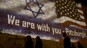 People walk past a projection on the Old City wall in Jerusalem, Sunday, Oct. 28, 2018 in a commemoration of the victims of a deadly shooting at a Pittsburgh synagogue. (Dusan Vranic/AP)