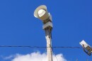 Photo of a storm siren with a blue sky background.