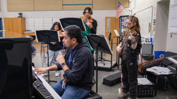 Serjoe Gutierrez sits at a piano to work with his first violinists to focus on intonation.
