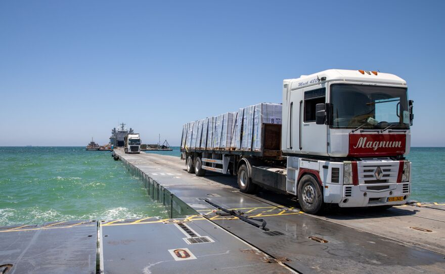 A DoD-contracted driver transports humanitarian aid across the Trident Pier, and onto the beach in Gaza.